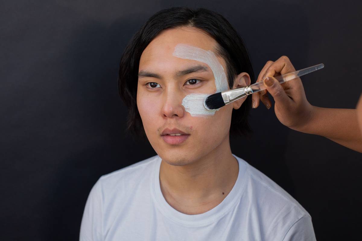 Close-up of model's cheek showing smooth primer application on one side versus unprimed, textured skin on the other