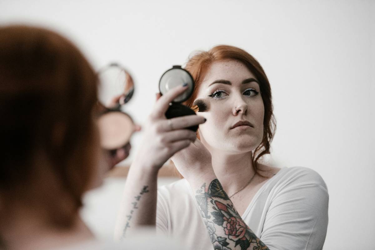 Makeup artist applying powder set technique on model's under-eye area with a damp sponge